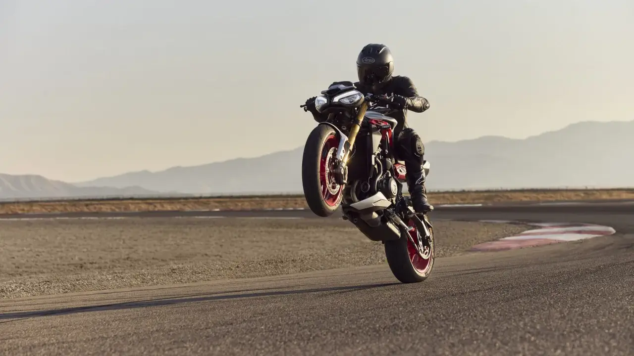Motocyklista na torze wykonuje wheelie. System kontroli trakcji co to? Pomaga utrzymać przyczepność podczas takich manewrów.