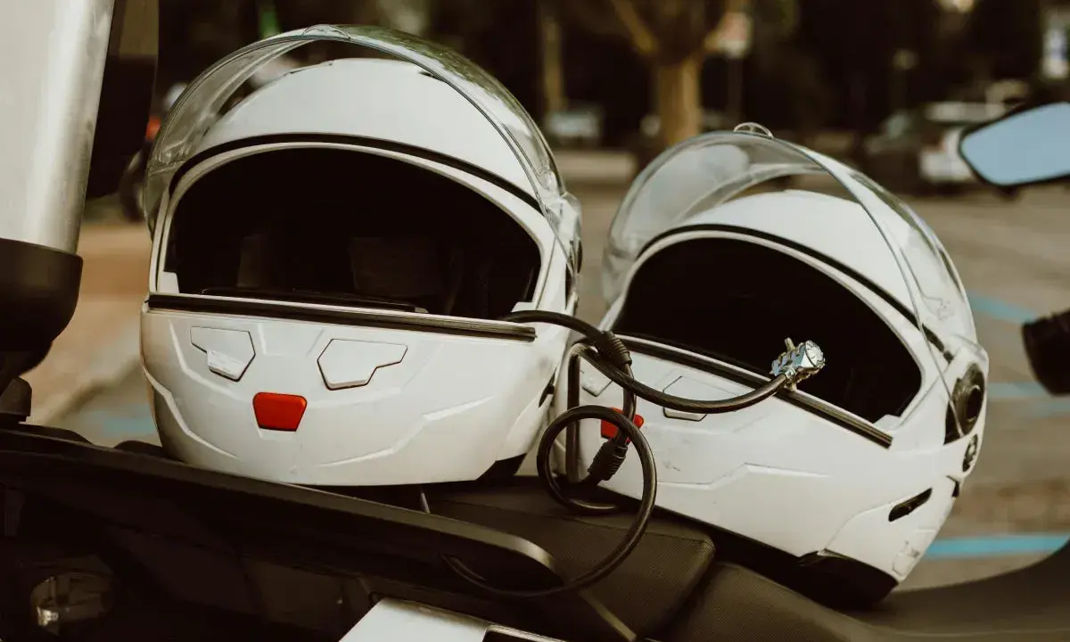 Dwa białe kaski motocyklowe połączone blokadą. Gotowe do podróży, czekają na właścicieli.