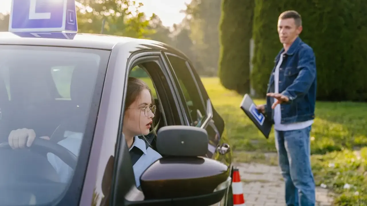 Młoda kursantka za kierownicą, instruktor objaśnia zasady. Zastanawia się, ile jest ważny egzamin teoretyczny na prawo jazdy.