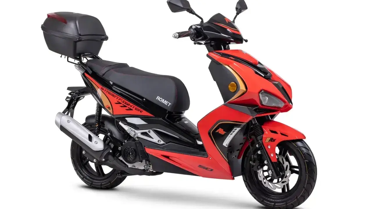 Czerwony skuter z czarnym siedzeniem i kufrem. Do jakiej pojemności można jeździć motorem bez prawa jazdy? Ten model to świetny wybór!