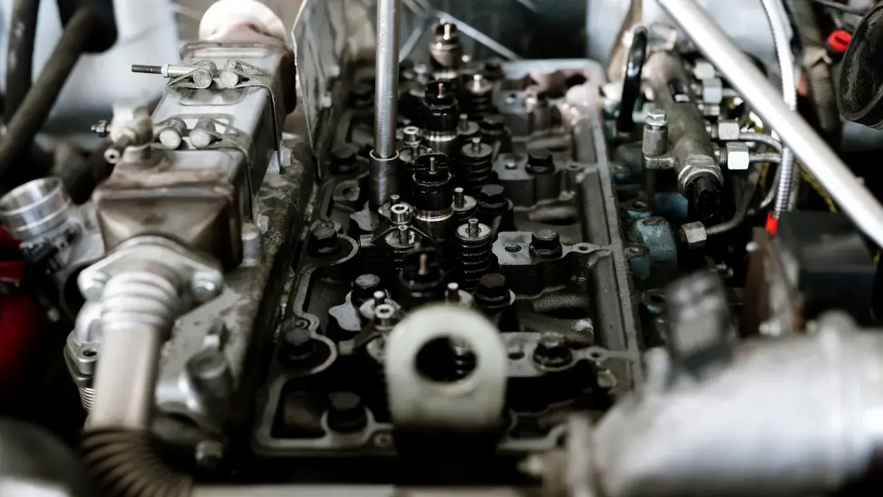 Wnętrze silnika z widocznymi zaworami i wtryskiwaczami. Mechanik sprawdza, czy nie występuje co to jest spalanie stukowe, które może uszkodzić jednostkę.