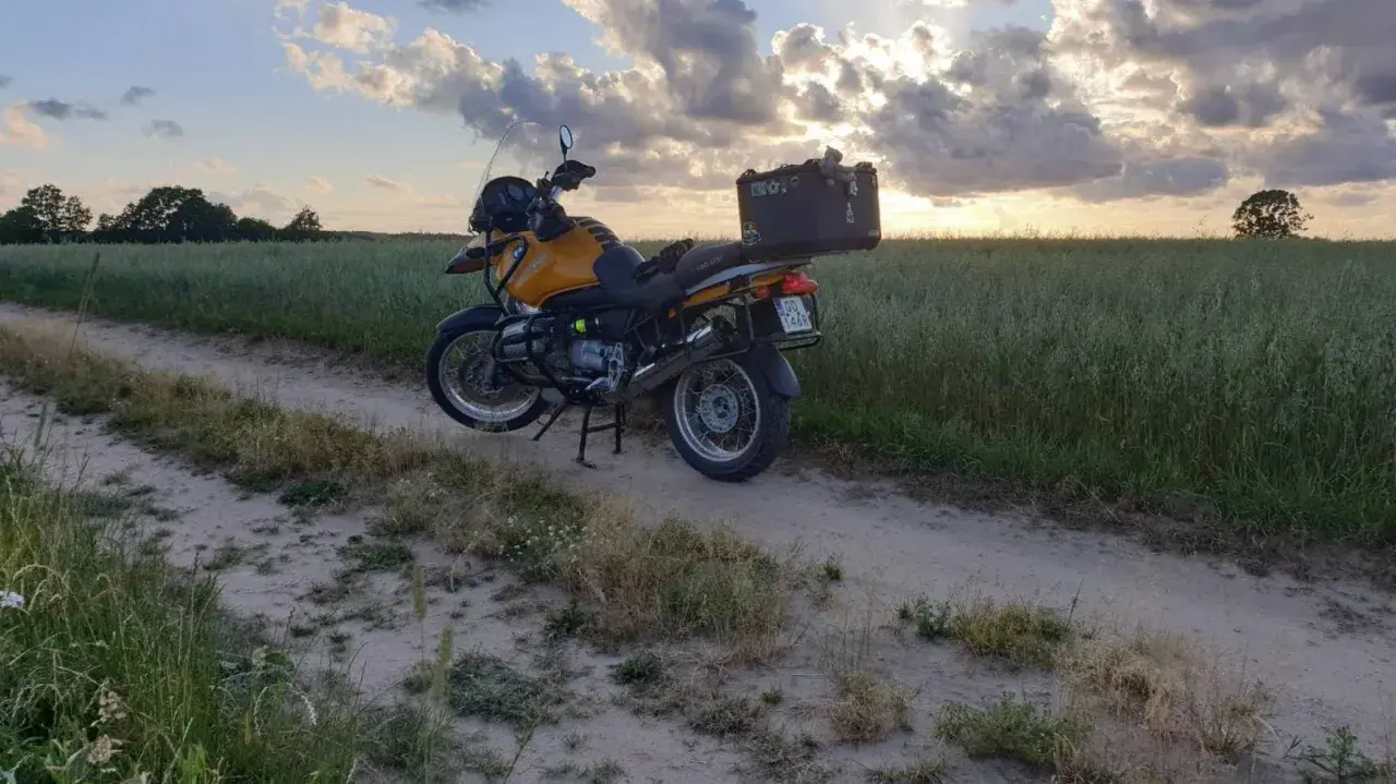Żółty motocykl turystyczny na piaszczystej drodze wśród pól. Idealne miejsce na odkrywanie tras motocyklowych Kaszuby.