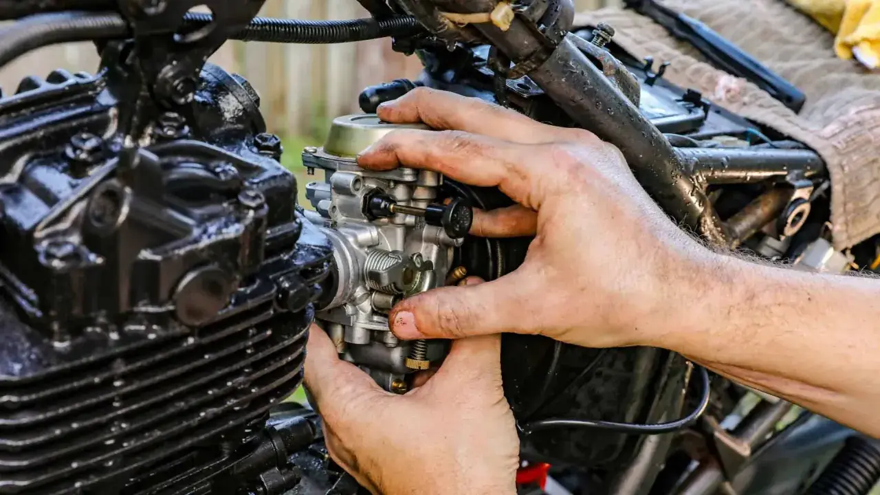 Dłonie mechanika regulują gaźnik motocykla, gdy ssanie jest włączone.