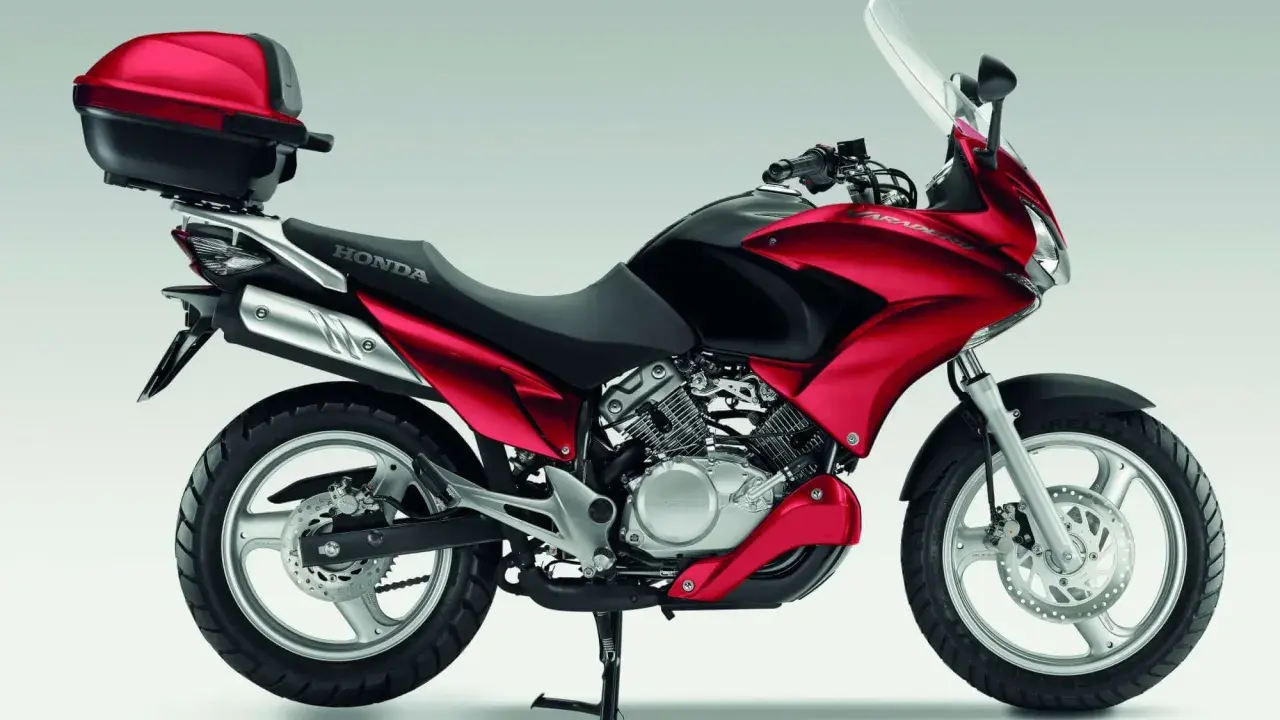 Czerwony motocykl Honda Varadero 125 z kufrem, gotowy na odblokowanie mocy i przygodę.