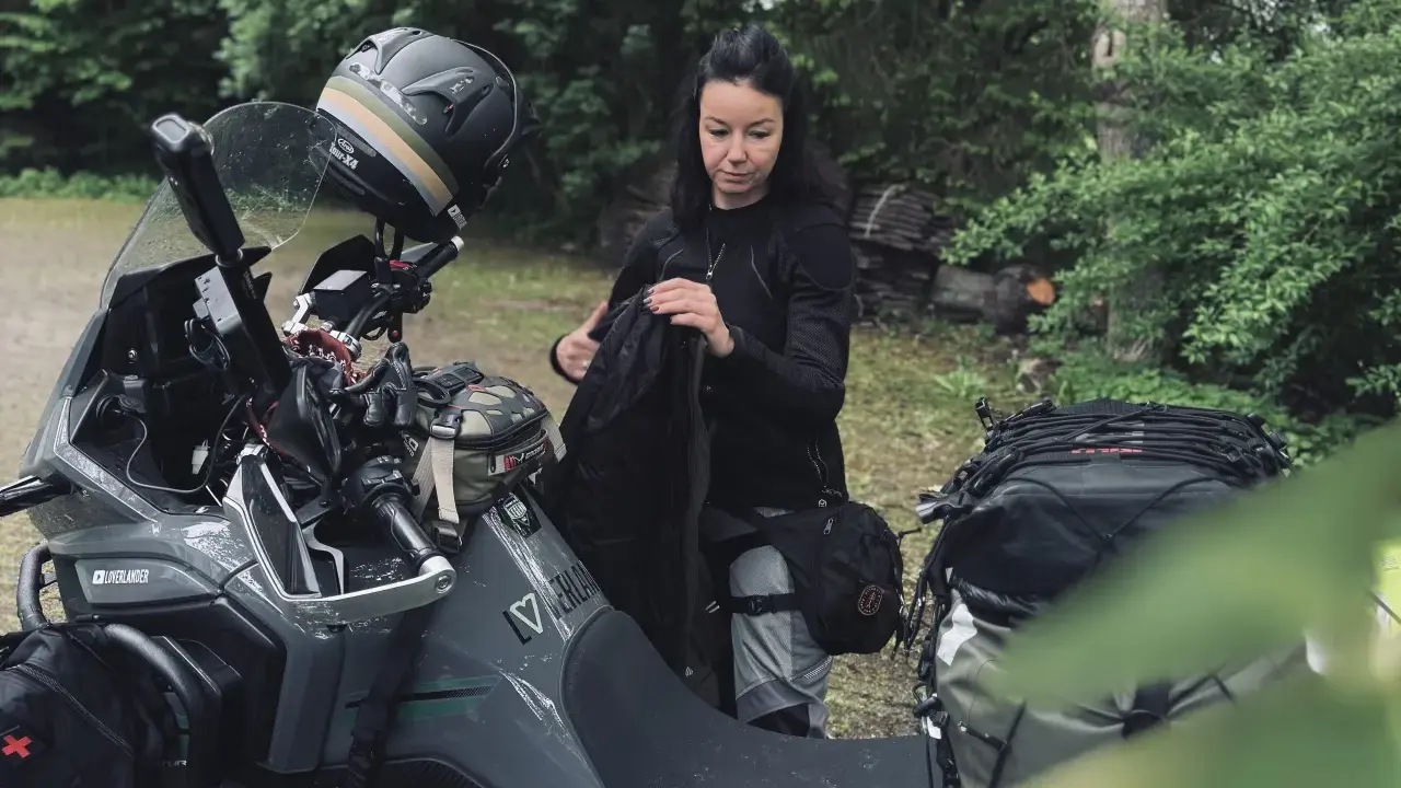 Kobieta pakuje plecak na motocykl. Zastanawia się, co zabrać na wyprawę motocyklową, by niczego nie zapomnieć.