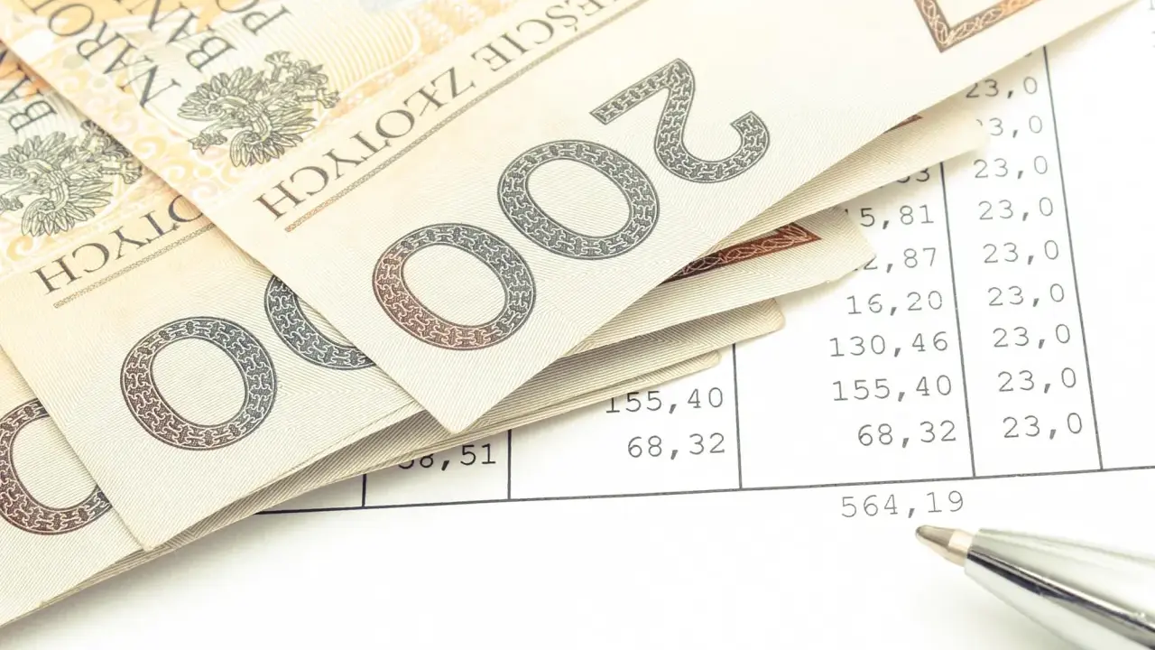 Polskie banknoty 200 zł leżą na arkuszu z wyliczeniami. Czy to podatek od kupna motocykla? Długopis wskazuje na kwotę.