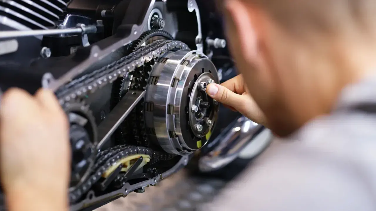 Mechanik pracuje nad mechanizmem motocykla, który umożliwia zmianę biegów bez sprzęgła.