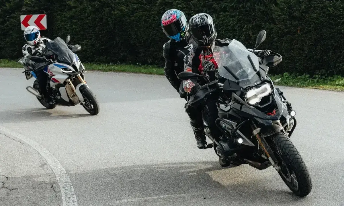 Motocykliści na zakręcie, jeden z pasażerem. Płynna zmiana biegów bez sprzęgła to klucz do dynamicznej jazdy.