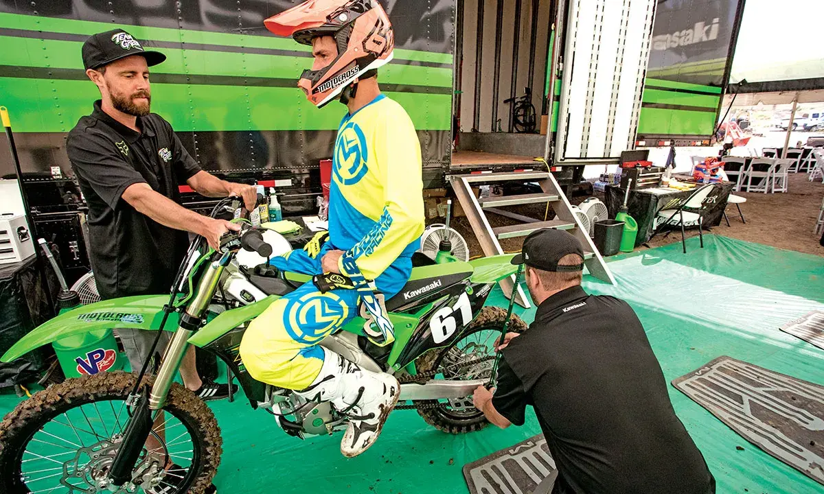 Mechanik sprawdza ustawienie sag w motocyklu, pomagając zawodnikowi w przygotowaniach do wyścigu.
