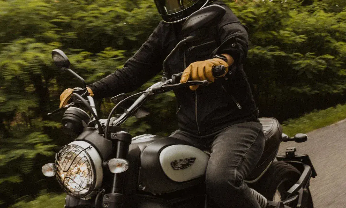 Motocyklista w kasku i żółtych rękawicach jedzie motocyklem. Zastanawia się, przy jakich obrotach zmieniać biegi, by jazda była płynna.
