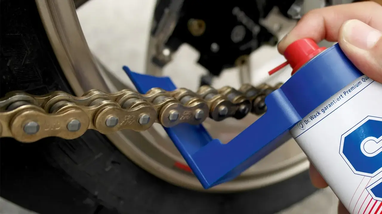 Czyszczenie i smarowanie łańcucha motocyklowego. Specjalny aplikator ułatwia dotarcie do wszystkich ogniw, pomagając w utrzymaniu napędu w idealnym stanie.