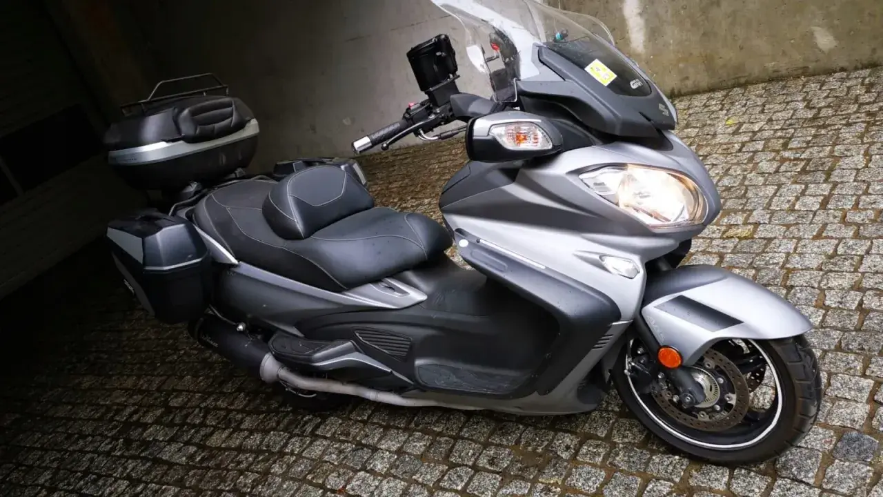 Srebrny Suzuki Burgman 650 z kuframi, gotowy do podróży. Czy są jakieś wady?