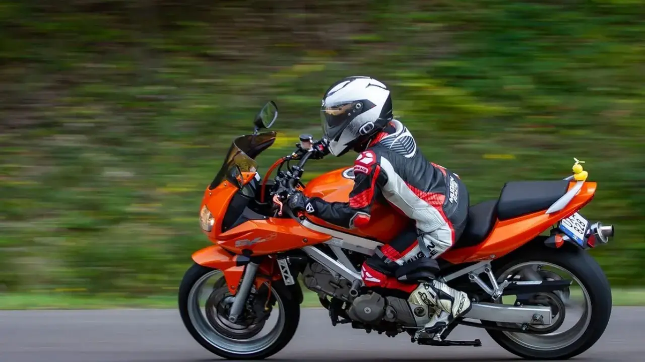 Motocyklista w kombinezonie śmiga pomarańczowym motocyklem. Idealna trasa motocyklowa Śląsk na weekendową przejażdżkę.