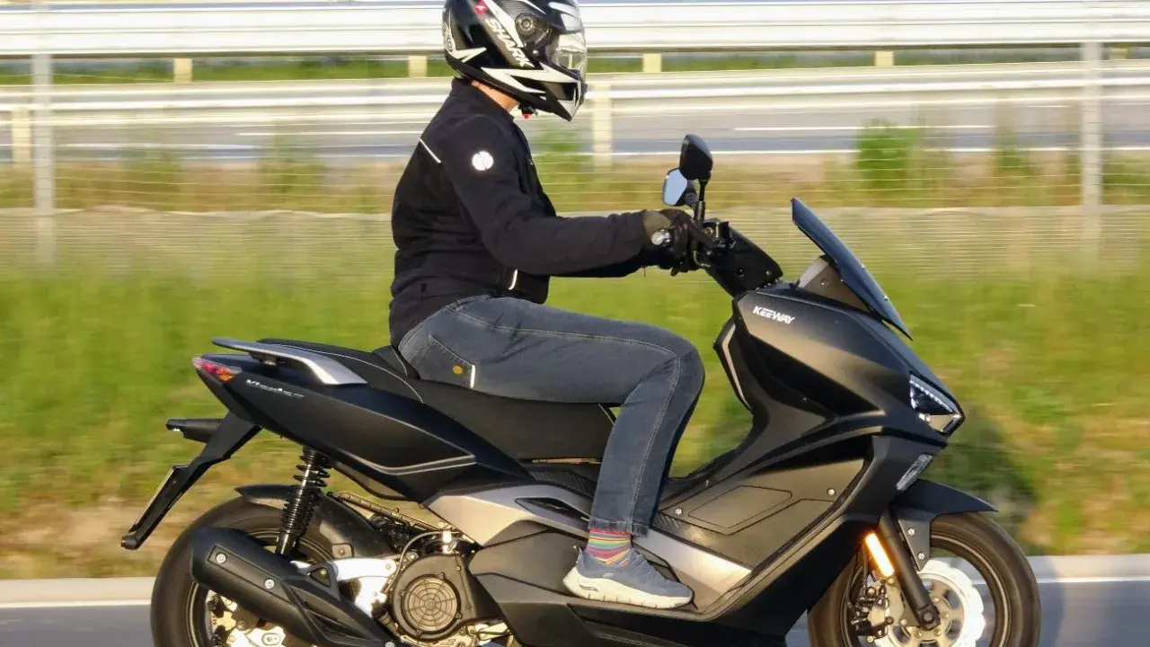 Mężczyzna w kasku i jeansach odbywa ekscytującą jazdę na skuterze Keeway.