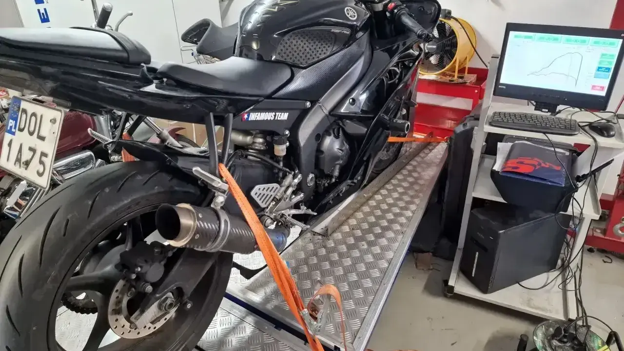 Czarny motocykl na hamowni, przygotowany do **blokowania motocykla na A2**. Pomiar mocy i momentu obrotowego.