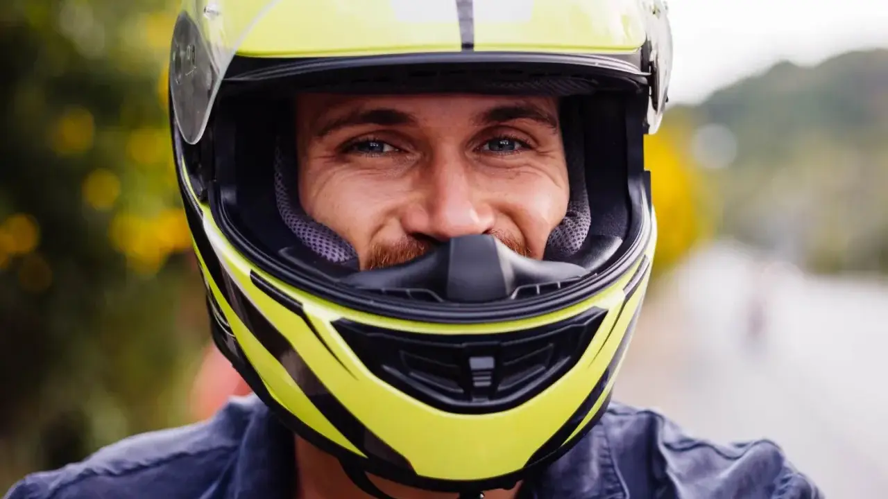Uśmiechnięty mężczyzna w żółtym kasku motocyklowym. Dobór odpowiednich rozmiarów kasków motocyklowych to klucz do bezpieczeństwa.