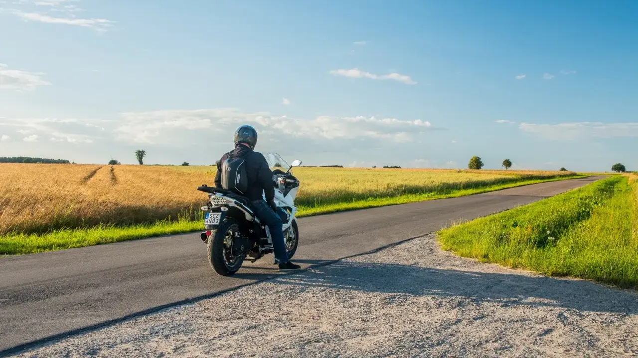 Motocyklista na tle pól pszenicy, odkrywa malownicze trasy motocyklowe mazowieckie.
