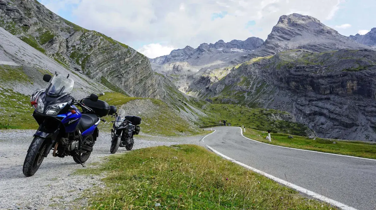 Dwa motocykle czekają na przygodę na krętej drodze przez alpejskie krajobrazy. Idealne trasy motocyklowe Austria!