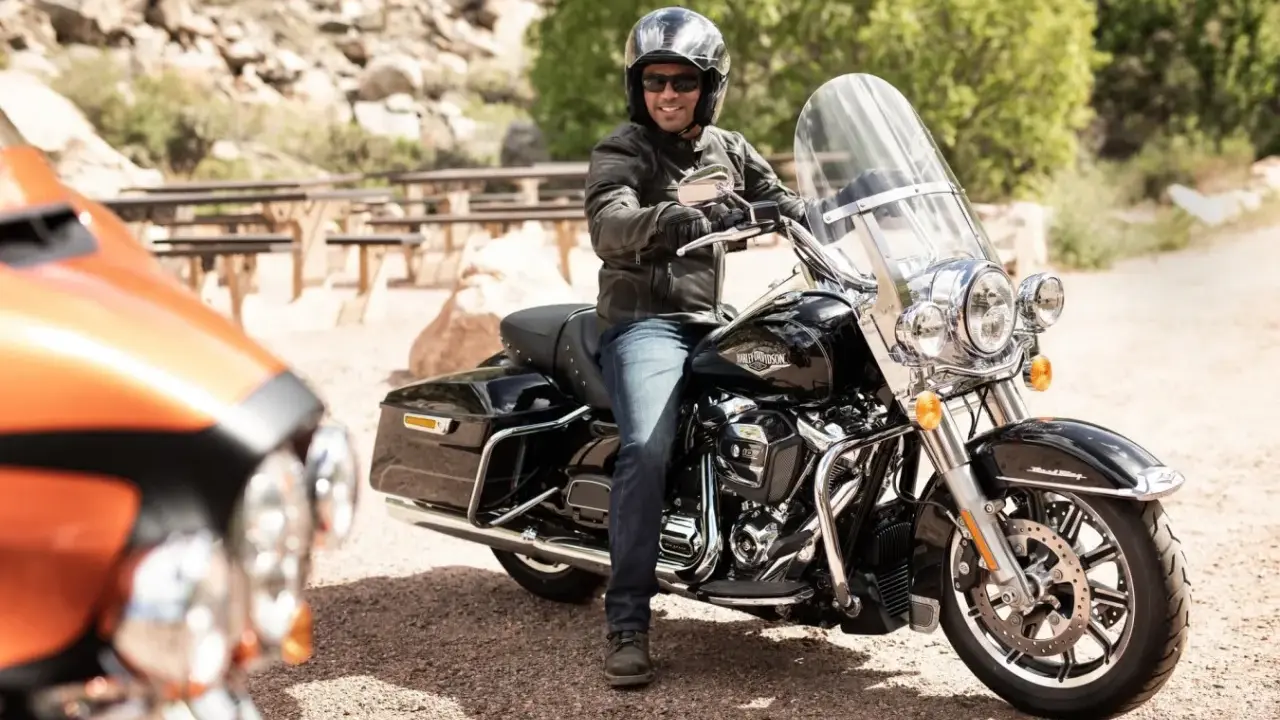 Mężczyzna na czarnym motocyklu Harley-Davidson, wyposażonym w gmole, gotowy na podróż.