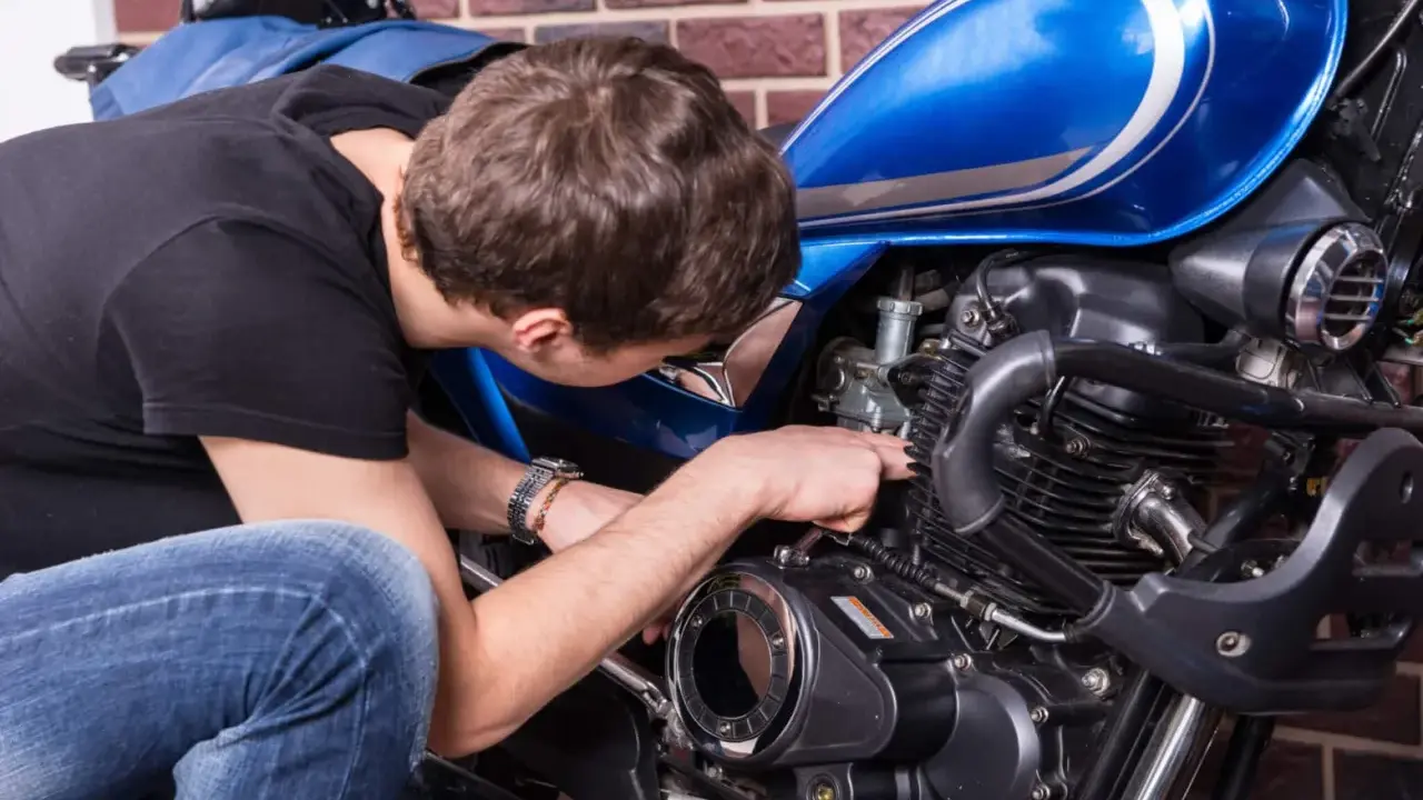 Mężczyzna naprawia niebieski motocykl. Czy to CBS?