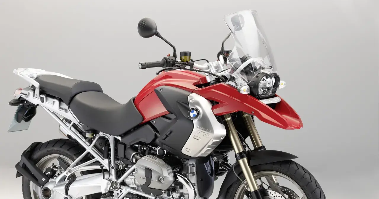 Czerwony motocykl BMW R1200GS z czarnym siedzeniem i dużą szybą.