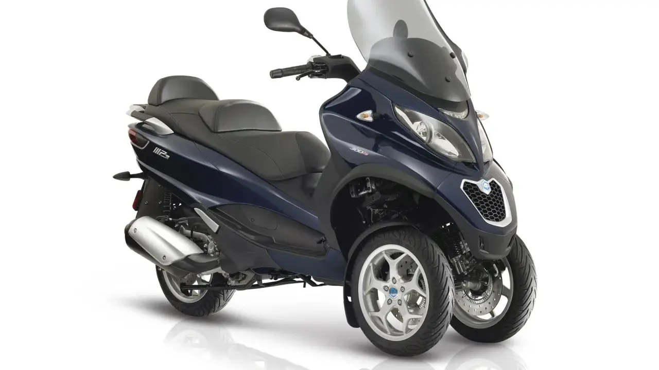 Granatowy Piaggio MP3 300 z trzema kołami, dużą szybą i wygodnym siedzeniem. Poznaj jego piaggio mp3 300 dane techniczne.