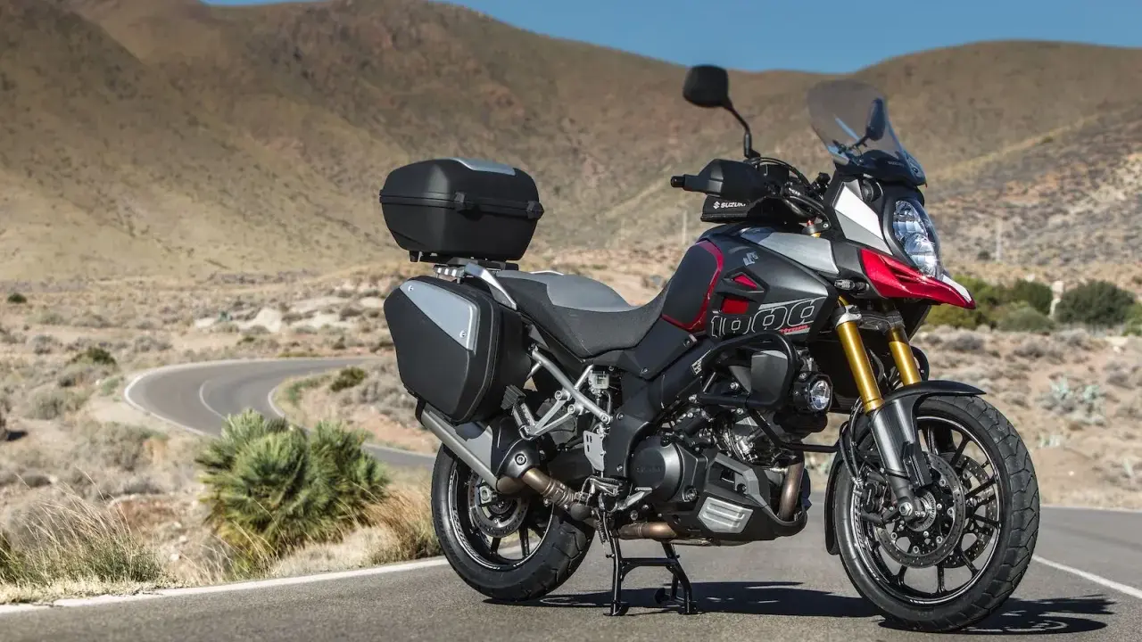 Suzuki DL 1000 V-Strom z kuframi, gotowy na przygodę na krętej drodze pośród pustynnych wzgórz.