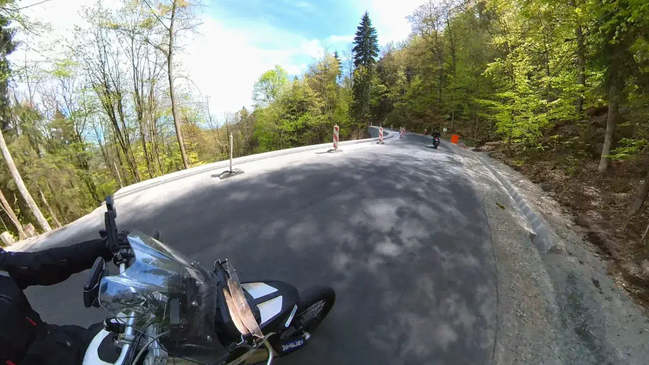 Motocyklista pokonuje zakręty najbardziej krętej drogi w Polsce, otoczonej bujną zielenią lasu.