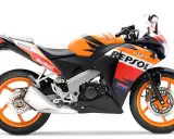 Pomarańczowo-czarny motocykl Honda CBR 125R w barwach Repsol, gotowy do jazdy z mocą V-max.