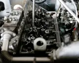 Wnętrze silnika z widocznymi zaworami i wtryskiwaczami. Mechanik sprawdza, czy nie występuje co to jest spalanie stukowe, które może uszkodzić jednostkę.