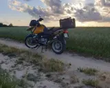 Żółty motocykl turystyczny na piaszczystej drodze wśród pól. Idealne miejsce na odkrywanie tras motocyklowych Kaszuby.