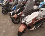 Kilka skuterów, w tym brązowy zipp qr max 125, stoi na chodniku.