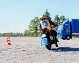 Osoba na motocyklu z literą "L" na kamizelce i tablicy, ćwiczy jazdę. Mam prawo jazdy B, chcę zrobić A.