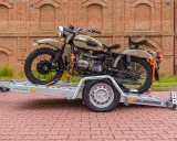 Motocykl Ural zabezpieczony pasami na przyczepie, pokazujący, jak przewieźć motocykl na zwykłej przyczepie.