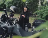 Kobieta pakuje plecak na motocykl. Zastanawia się, co zabrać na wyprawę motocyklową, by niczego nie zapomnieć.