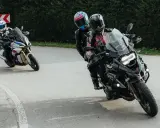 Motocykliści na zakręcie, jeden z pasażerem. Płynna zmiana biegów bez sprzęgła to klucz do dynamicznej jazdy.