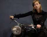 Kobieta na motocyklu, gotowa na odkrywanie tras motocyklowych zachodniopomorskie. Stylowy strój i pewność siebie.