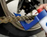 Czyszczenie i smarowanie łańcucha motocyklowego. Specjalny aplikator ułatwia dotarcie do wszystkich ogniw, pomagając w utrzymaniu napędu w idealnym stanie.