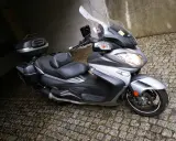 Srebrny Suzuki Burgman 650 z kuframi, gotowy do podróży. Czy są jakieś wady?