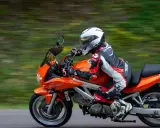 Motocyklista w kombinezonie śmiga pomarańczowym motocyklem. Idealna trasa motocyklowa Śląsk na weekendową przejażdżkę.