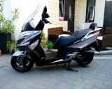 Elegancki skuter Kymco Dink 50 w kolorze grafitowym stoi na podjeździe, gotowy do jazdy.