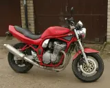 Czerwony Suzuki Bandit 600, gotowy do jazdy, z widocznym silnikiem i wydechem.