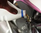 Rękawica nalewa nowy olej do silnika motocykla podczas wymiany oleju.