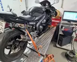 Czarny motocykl na hamowni, przygotowany do **blokowania motocykla na A2**. Pomiar mocy i momentu obrotowego.