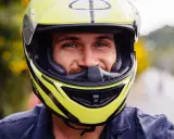 Uśmiechnięty mężczyzna w żółtym kasku motocyklowym. Dobór odpowiednich rozmiarów kasków motocyklowych to klucz do bezpieczeństwa.