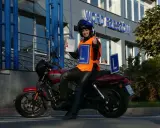Uśmiechnięta motocyklistka z dokumentem w ręku i kciukiem w górze, gotowa na egzamin teoretyczny kat A.