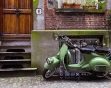 Zielony skuter, klasyk, czeka na właściciela. Parkowanie motocykla na chodniku przed drzwiami z numerem 9.