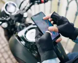 Motocyklista w rękawiczkach sprawdza trasę na mapie w aplikacji dla motocyklistów.