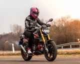 Motocyklistka w kolorowym kasku pędzi na czarnym motocyklu. Zastanawiasz się, ile waży litr benzyny, gdy tankujesz przed podróżą?
