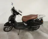 Czarny skuter Romet Retro 7 50 z brązowym siedzeniem i chromowanymi elementami, gotowy na retro podróż.